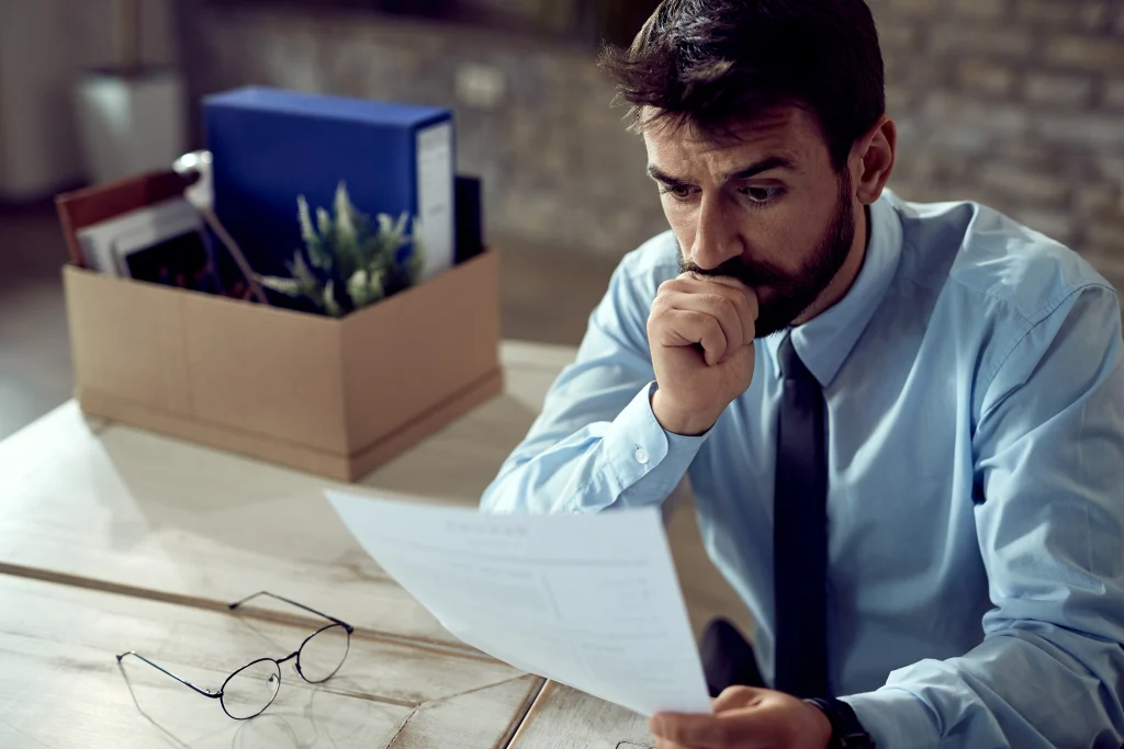 Homme en chemise consultant des documents administratifs après avoir perdu son emploi, une situation fréquente chez les expatriés confrontés au chômage en Espagne