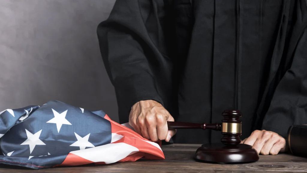 Main d’un juge frappant avec un marteau devant un drapeau américain, illustrant le cadre légal du travail aux États-Unis.