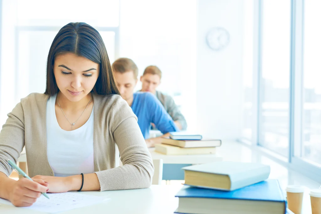 Élève concentrée en classe dans une salle d'examen, illustrant une scène typique du système scolaire en Espagne au niveau secondaire.