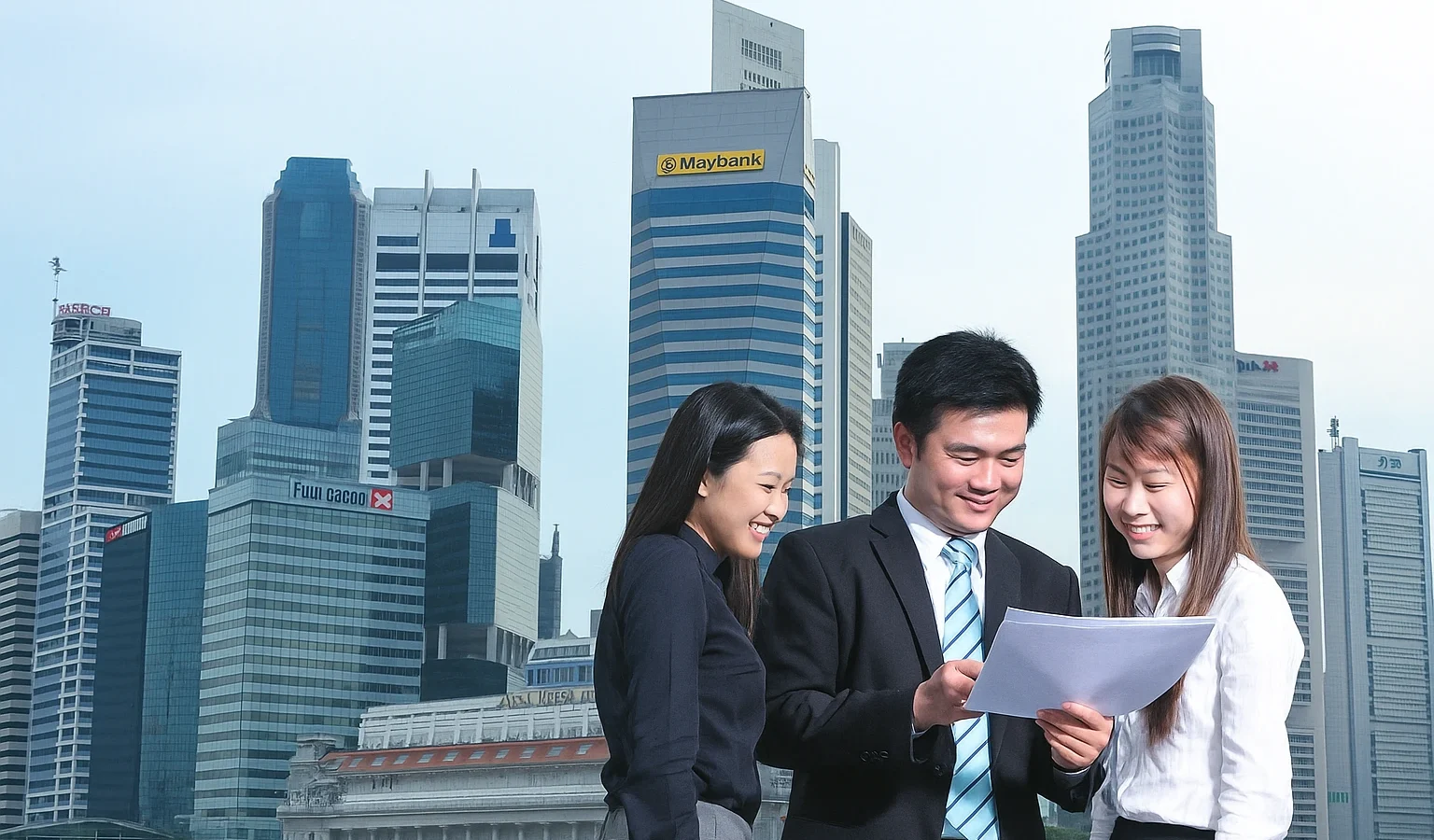 Jeunes professionnels discutant de documents devant les gratte-ciel de Singapour