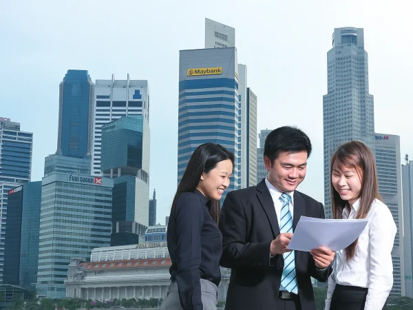 Young professionals discussing documents in front of Singapore’s skyscrapers