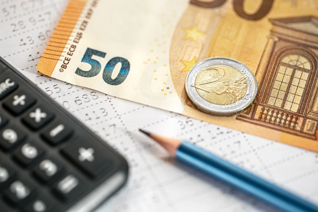 Calculatrice, billet de 50 euros et crayon sur un document fiscal — une image illustrant le calcul des impôts en Espagne pour les expatriés.