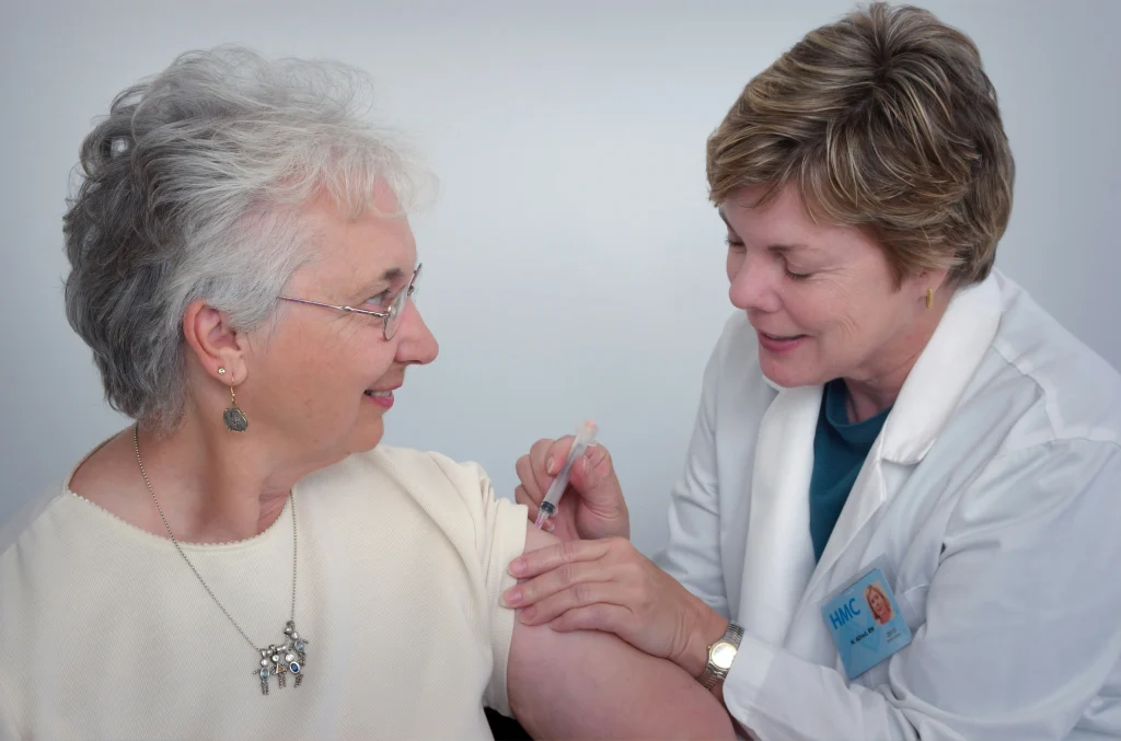 Doctor administering a vaccine to a pensioner in Portugal as part of healthcare