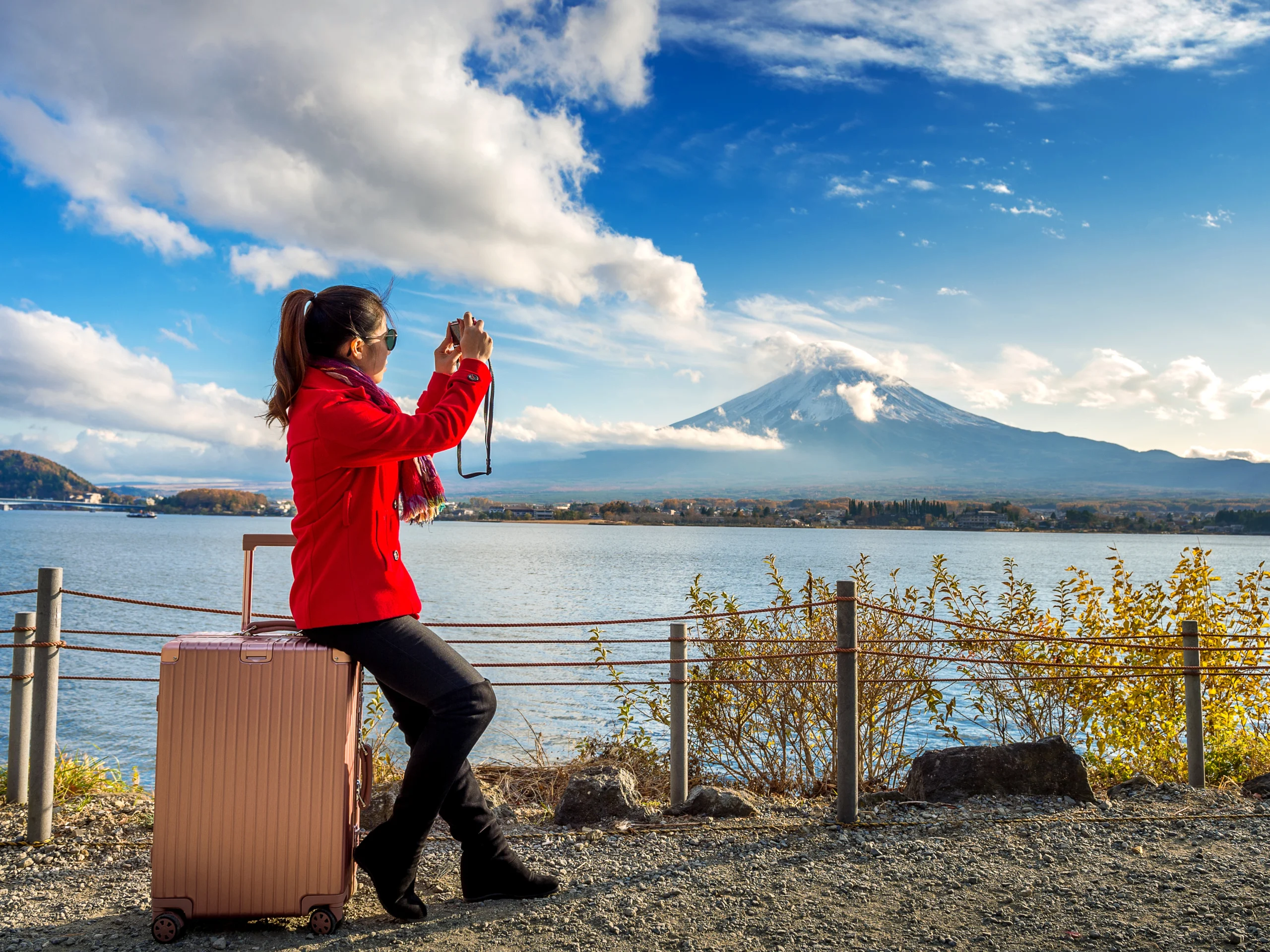 Visa for Japan: a women sitting on her suitcase taking pictures of the fascinating Mount Fuji in Japan
