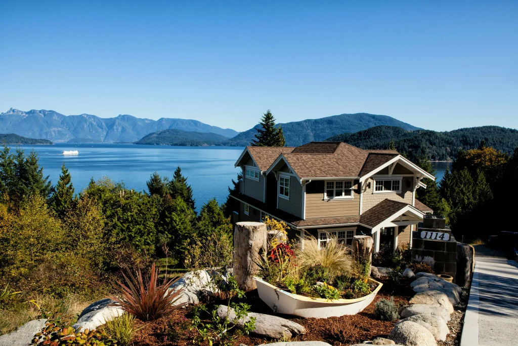 Maison résidentielle avec vue panoramique sur un lac et les montagnes, représentant un bien immobilier typique dans l’Ouest canadien, idéal pour les expatriés français souhaitant acheter une maison au Canada.