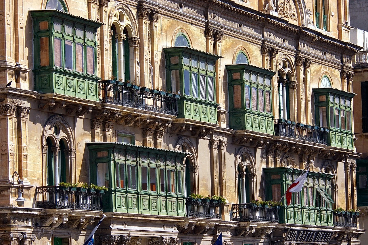 Façade d'un bâtiment traditionnel maltais avec des balcons en bois vert caractéristiques, représentant l'architecture typique de Malte.