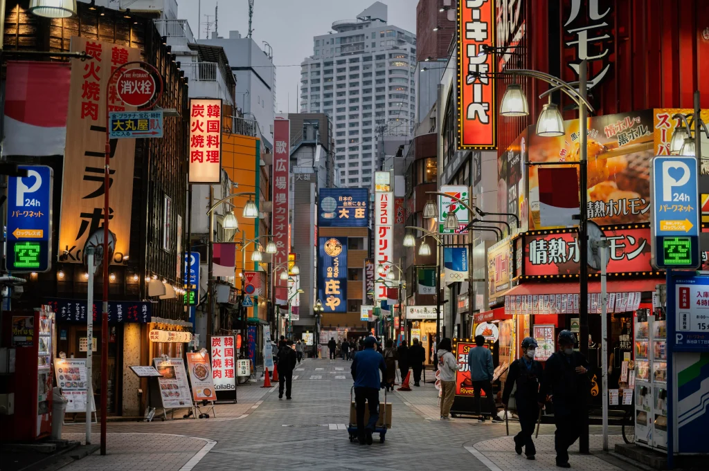 Rue japonaise animée bordée de restaurants et de néons, reflétant la vie urbaine dynamique qui attire de nombreux expatriés.