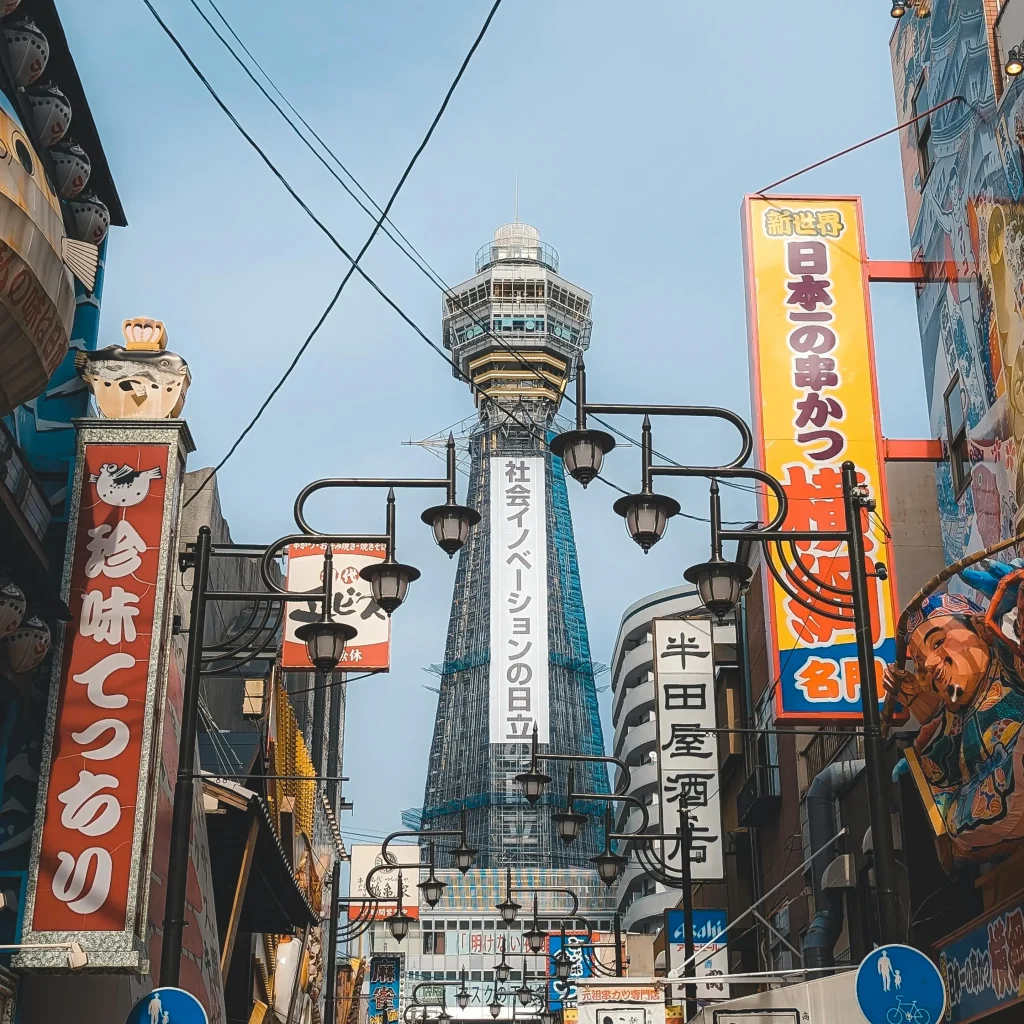 Rue commerçante d’Osaka avec la tour Tsutenkaku en arrière-plan, représentant l’énergie urbaine proche des logements disponibles.