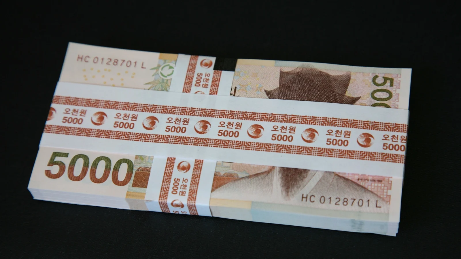 Une liasse de billets de 5 000 wons coréens, la monnaie officielle de la Corée du Sud, posée sur une surface noire.