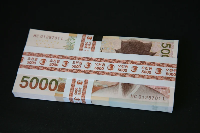 Une liasse de billets de 5 000 wons coréens, la monnaie officielle de la Corée du Sud, posée sur une surface noire.