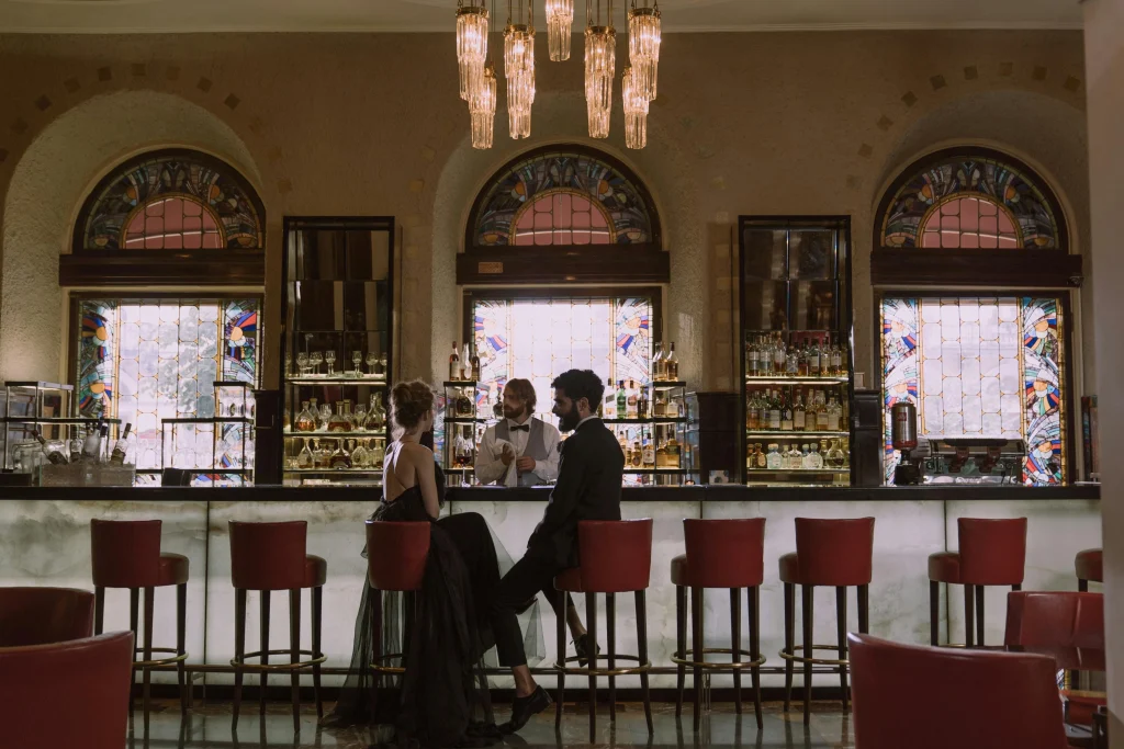 Bar avec des bouteilles et des verres sur le comptoir. Deux personnes sont sur des chaises