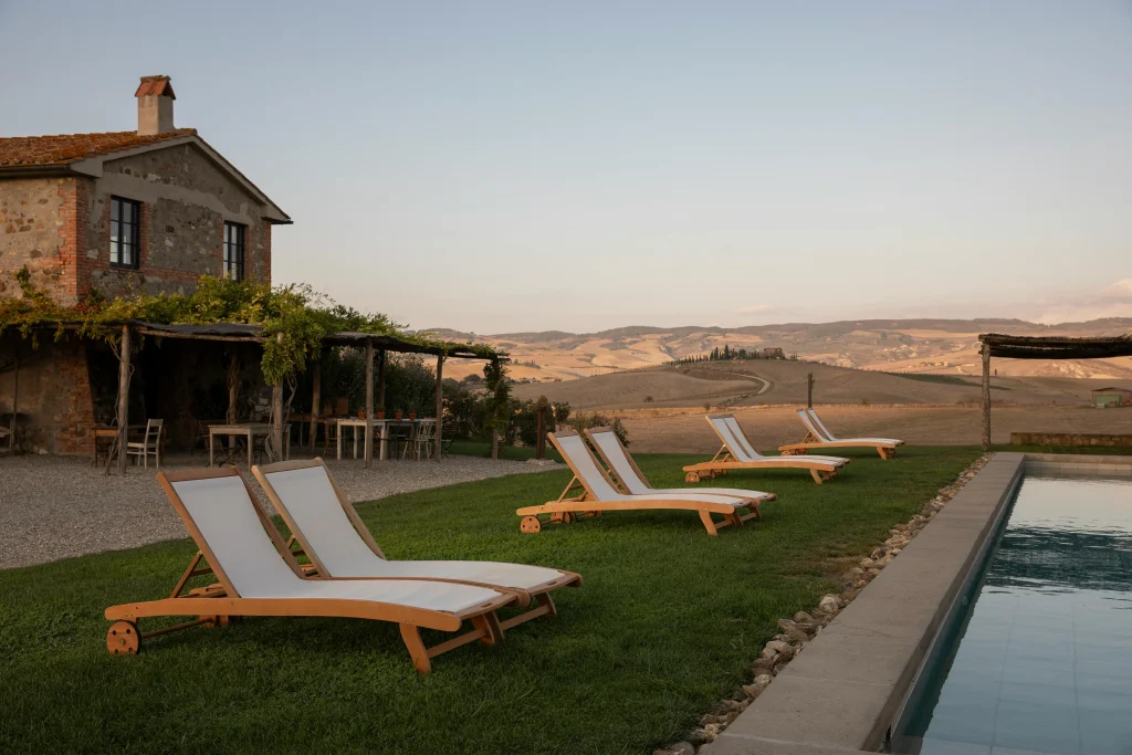 A luxurious Tuscan villa with a pool and lounge chairs overlooking rolling hills, offering a glimpse into high-end accommodation options. Renting in Italy provides opportunities for exclusive stays in beautiful countryside settings.