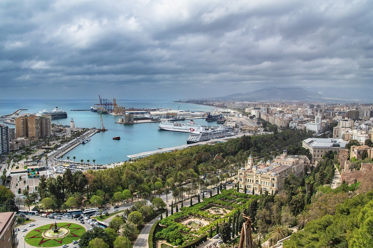 A panoramic view of Málaga’s harbour, green parks, and cityscape with mountains in the background, capturing the city's mix of coastal and urban charm.