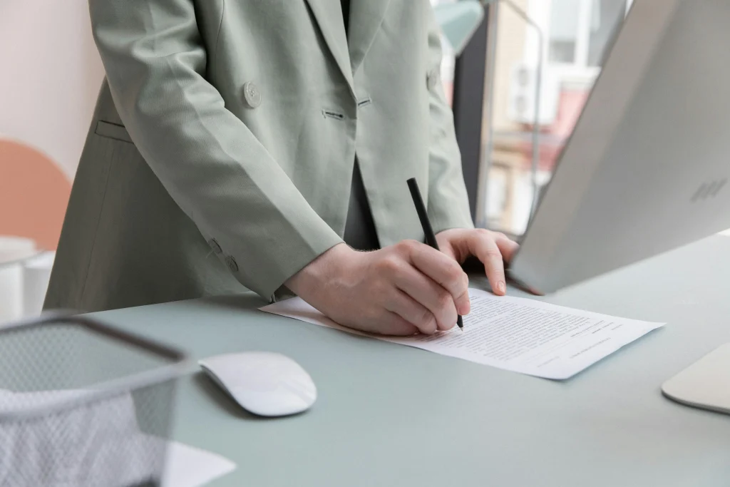 A person signing a rental agreement, illustrating the importance of legal paperwork when securing a home. Understanding contracts is crucial when Renting in Italy, whether for short-term stays or long-term leases.
