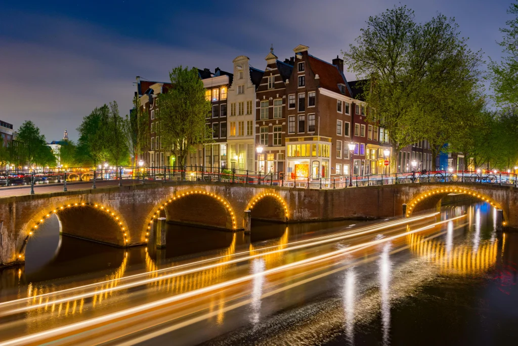 Illuminated canal bridge in Amsterdam at night, showcasing the city’s iconic architecture and vibrant atmosphere, perfect for exploring the best areas to stay.