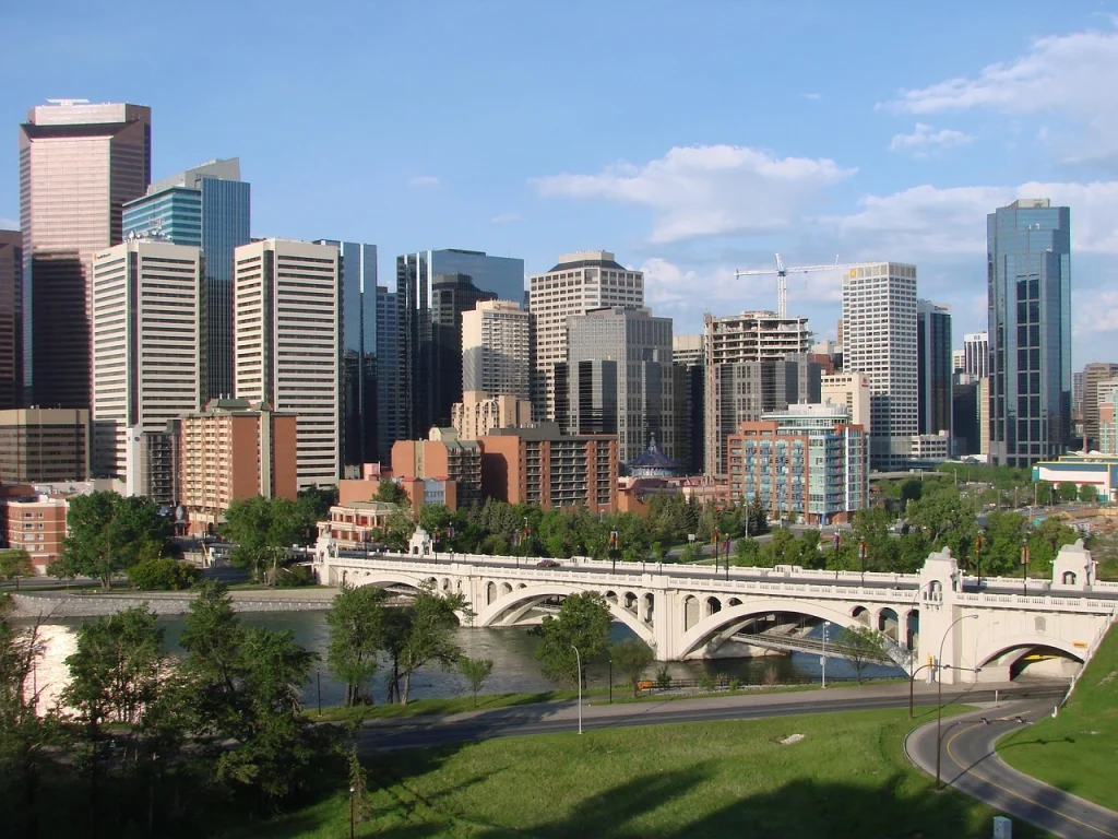 Calgary cityscape with modern skyscrapers, a historic bridge, and scenic river views, showcasing the balance between urban development and natural beauty.