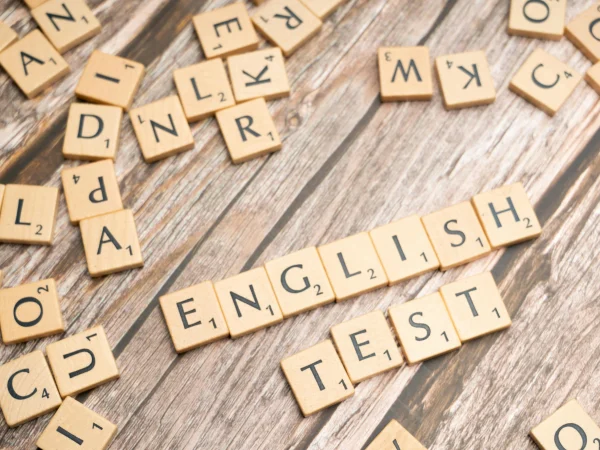 Des lettres de Scrabble formant les mots "English Test" sur une surface en bois, représentant les tests de compétence en anglais et l’évaluation linguistique.