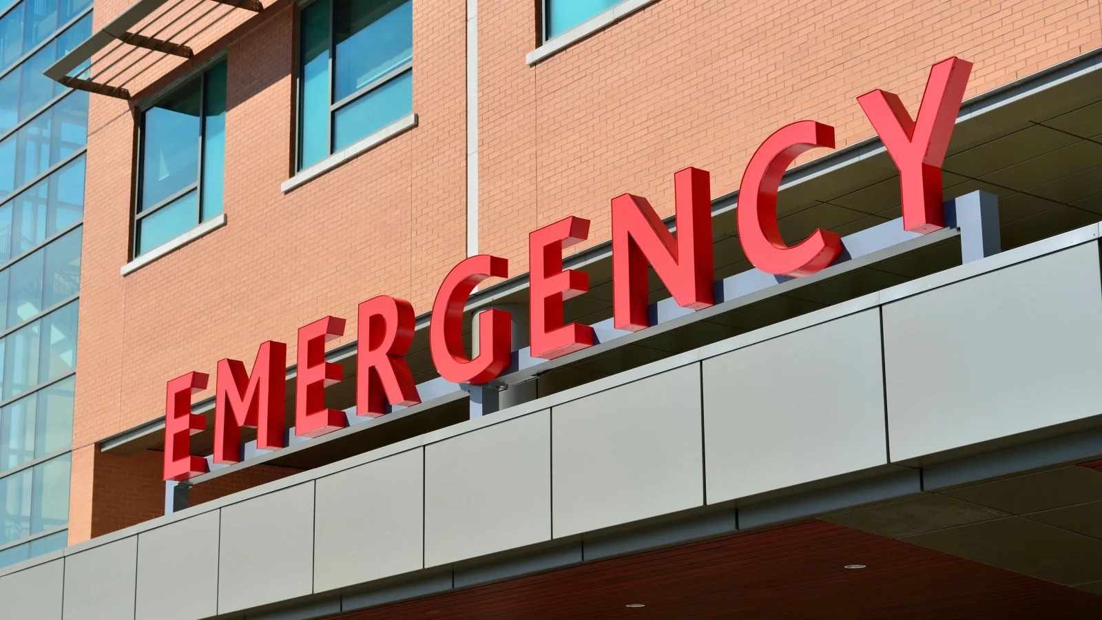 A bold red 'Emergency' sign at a hospital entrance, representing urgent care services in the Belgium Healthcare system.