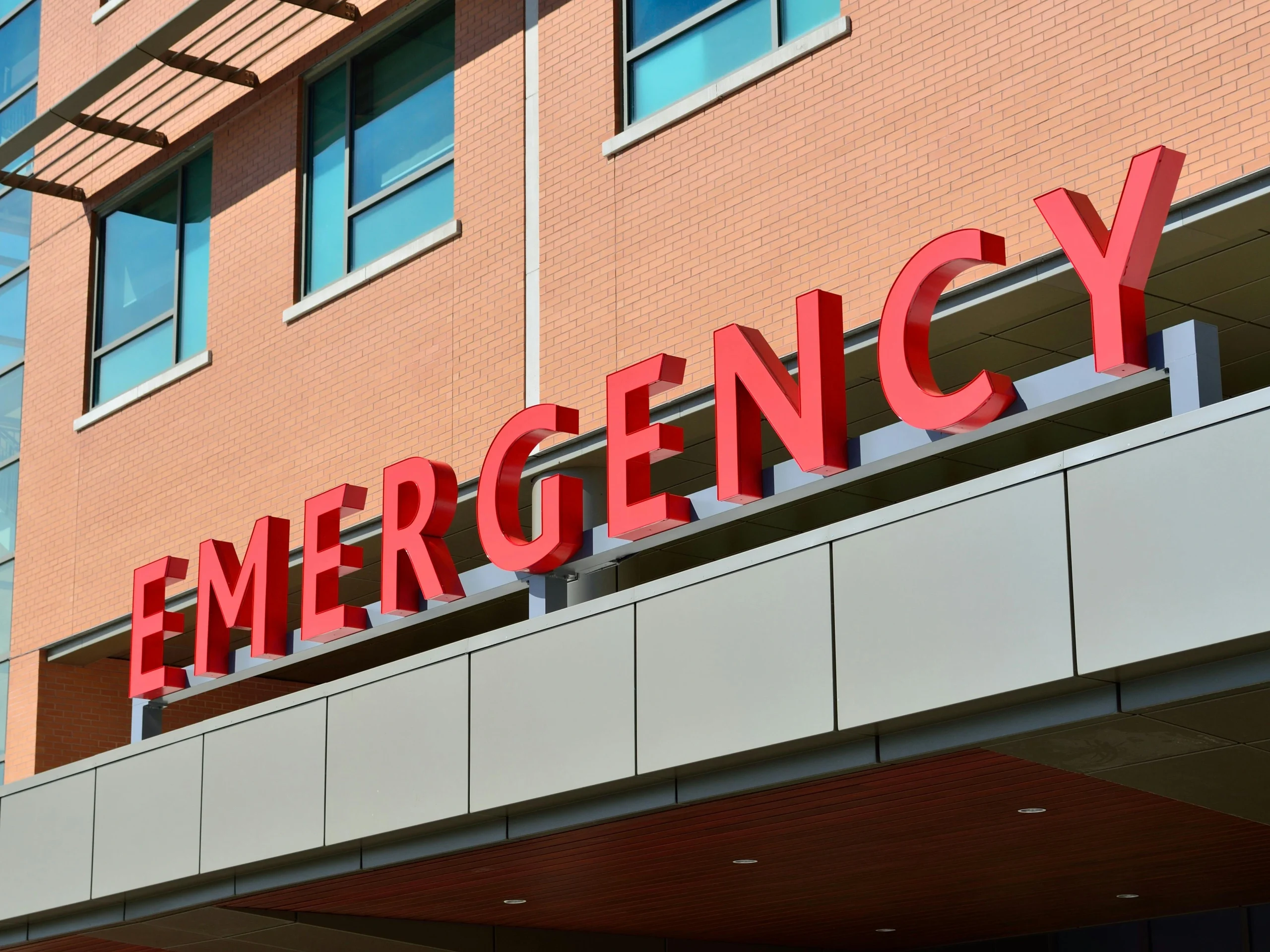 A bold red 'Emergency' sign at a hospital entrance, representing urgent care services in the Belgium Healthcare system.