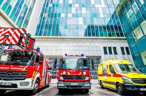 Fire trucks and an ambulance outside a modern hospital, highlighting emergency response within the Belgium Healthcare system.