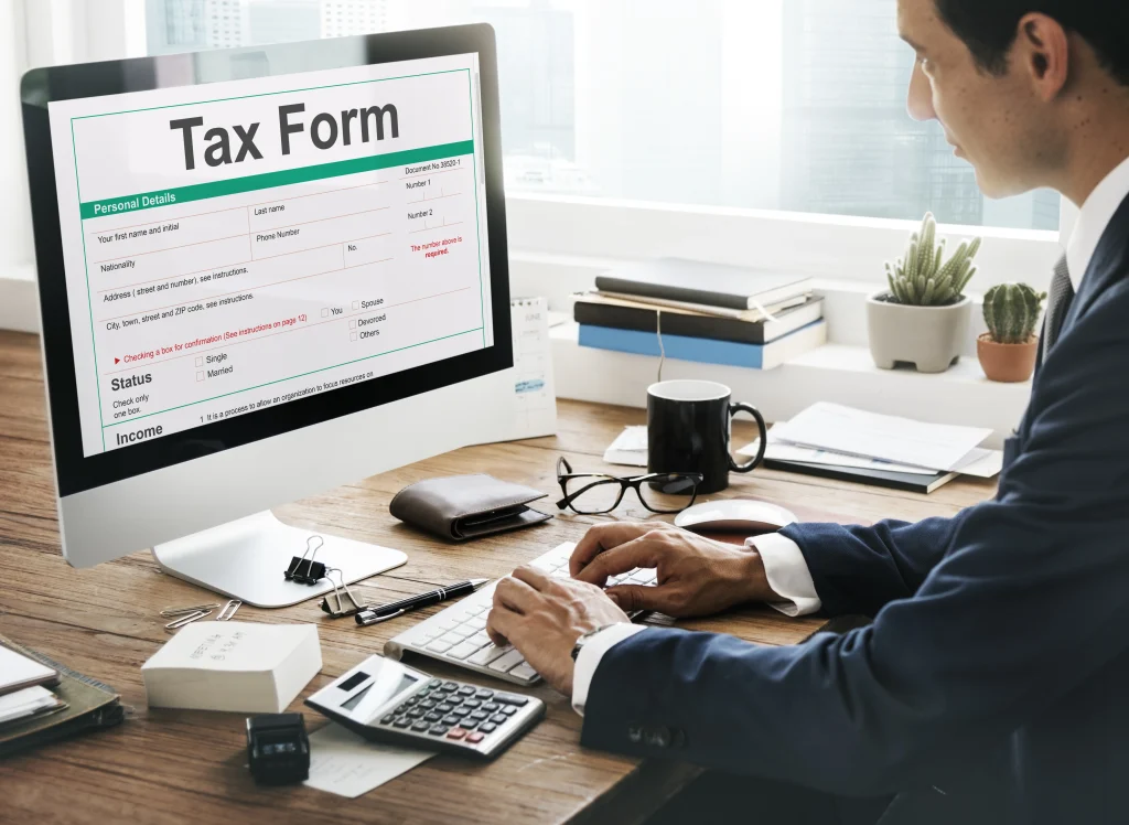 Businessman completing a digital tax form on a desktop, representing income reporting and compliance with Taxes in China.