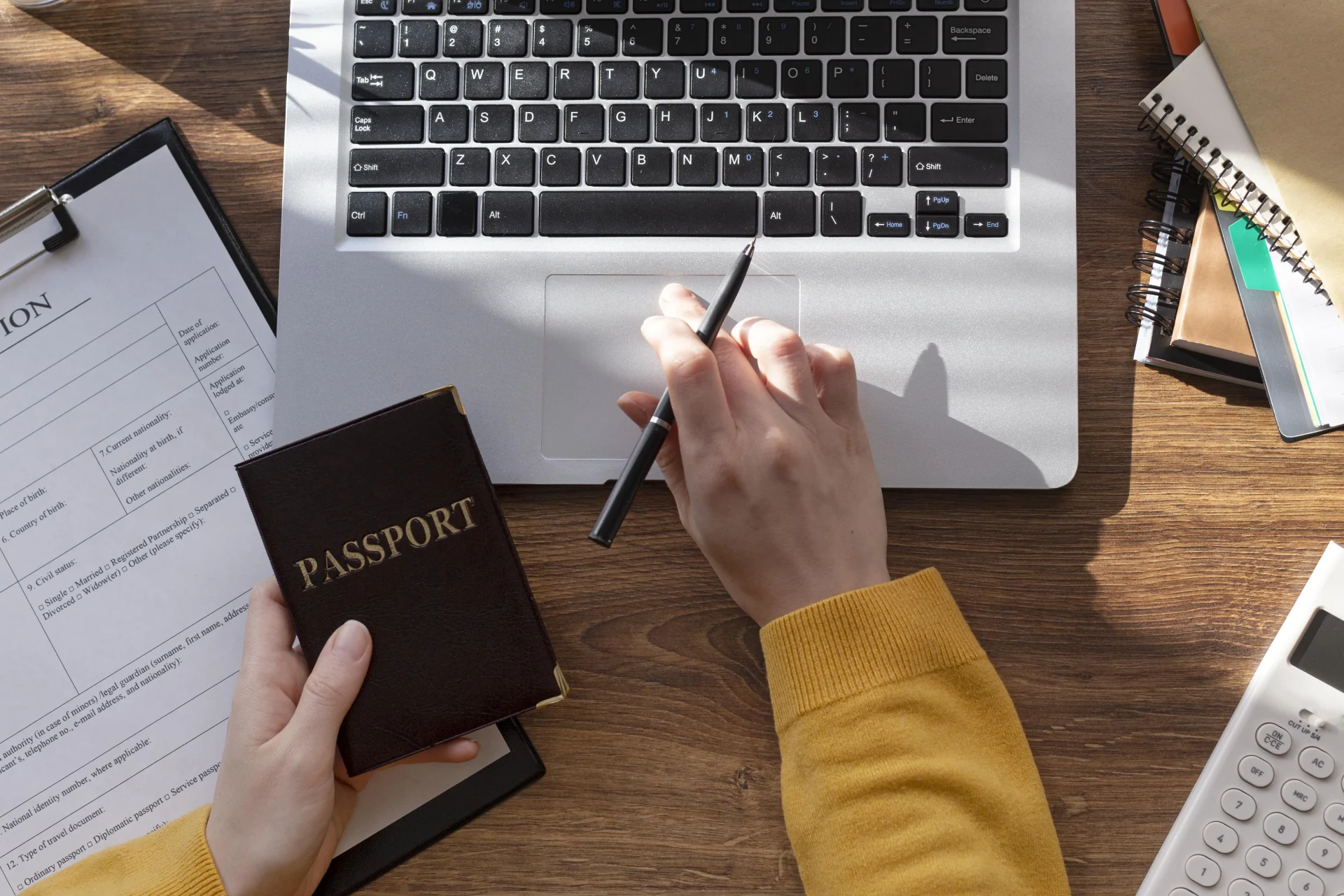 Personne saisissant les informations de la TDAC sur un ordinateur portable avec un passeport et des documents de voyage à proximité.