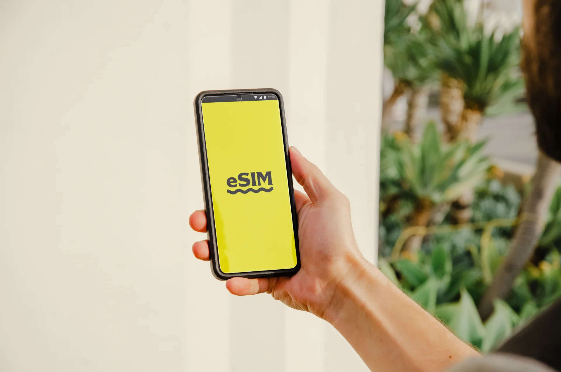 Person holding a smartphone displaying an eSIM logo, representing modern travel connectivity options through digital SIM technology.