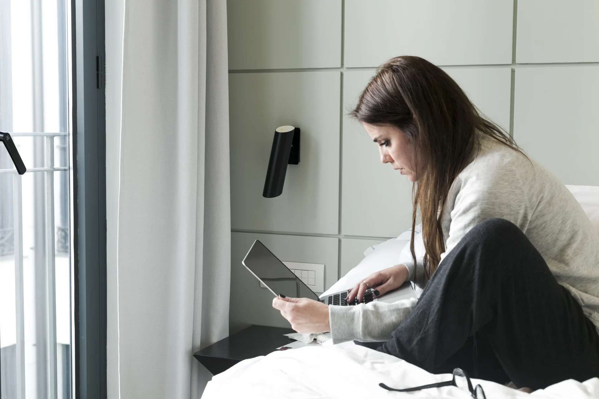 A woman researching housing in Colombia online from her bedroom, preparing for relocation and comparing rental options on her laptop.