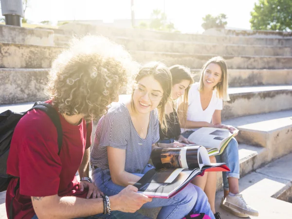 Étudiants internationaux en train d’étudier ensemble en plein air sur un campus ensoleillé d’une des meilleures universités en Suisse.