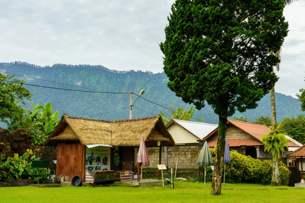 Traditional house with a thatched roof and lush garden at the foot of tropical mountains in the Philippines.