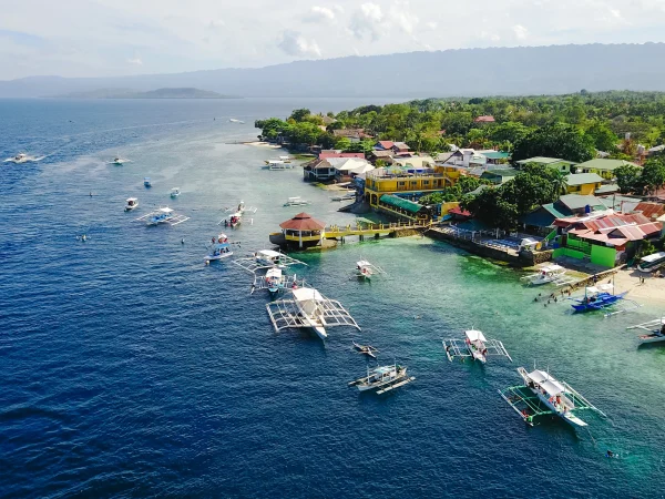 Aerial view of a coastal village with traditional boats and seaside housing in the Philippines.