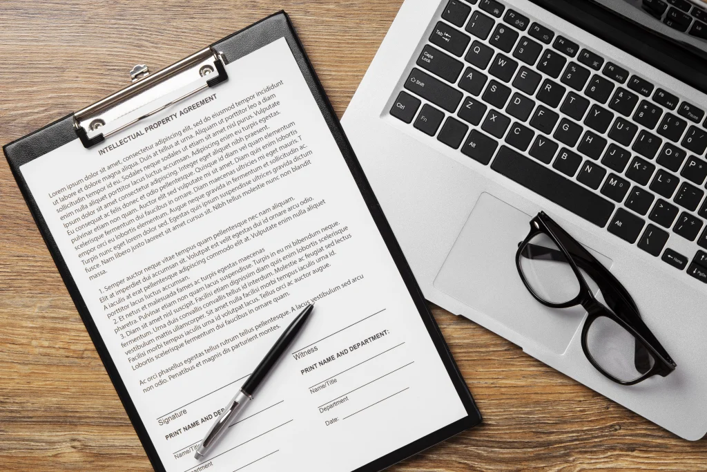Employment contract on a desk with pen, laptop, and glasses.