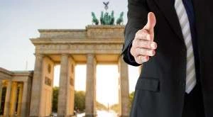 Handshake in front of the Brandenburg Gate in Berlin, symbolizing work in Germany and professional opportunities for expatriates.