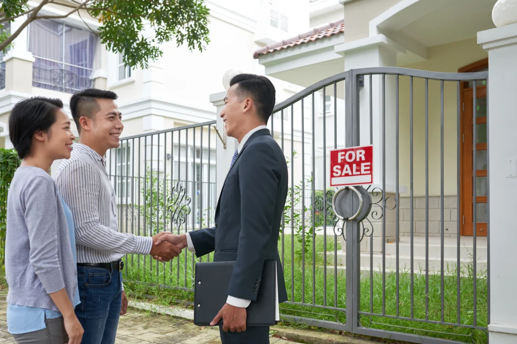 Agent immobilier coréen serrant la main d’un couple devant une logement en Corée du Sud à vendre.