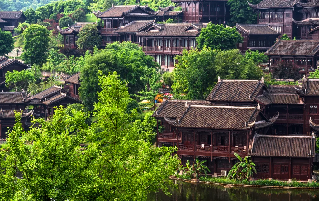 Maisons traditionnelles vietnamiennes entourées de verdure et bordées d’un lac, illustrant le charme de l’architecture locale.