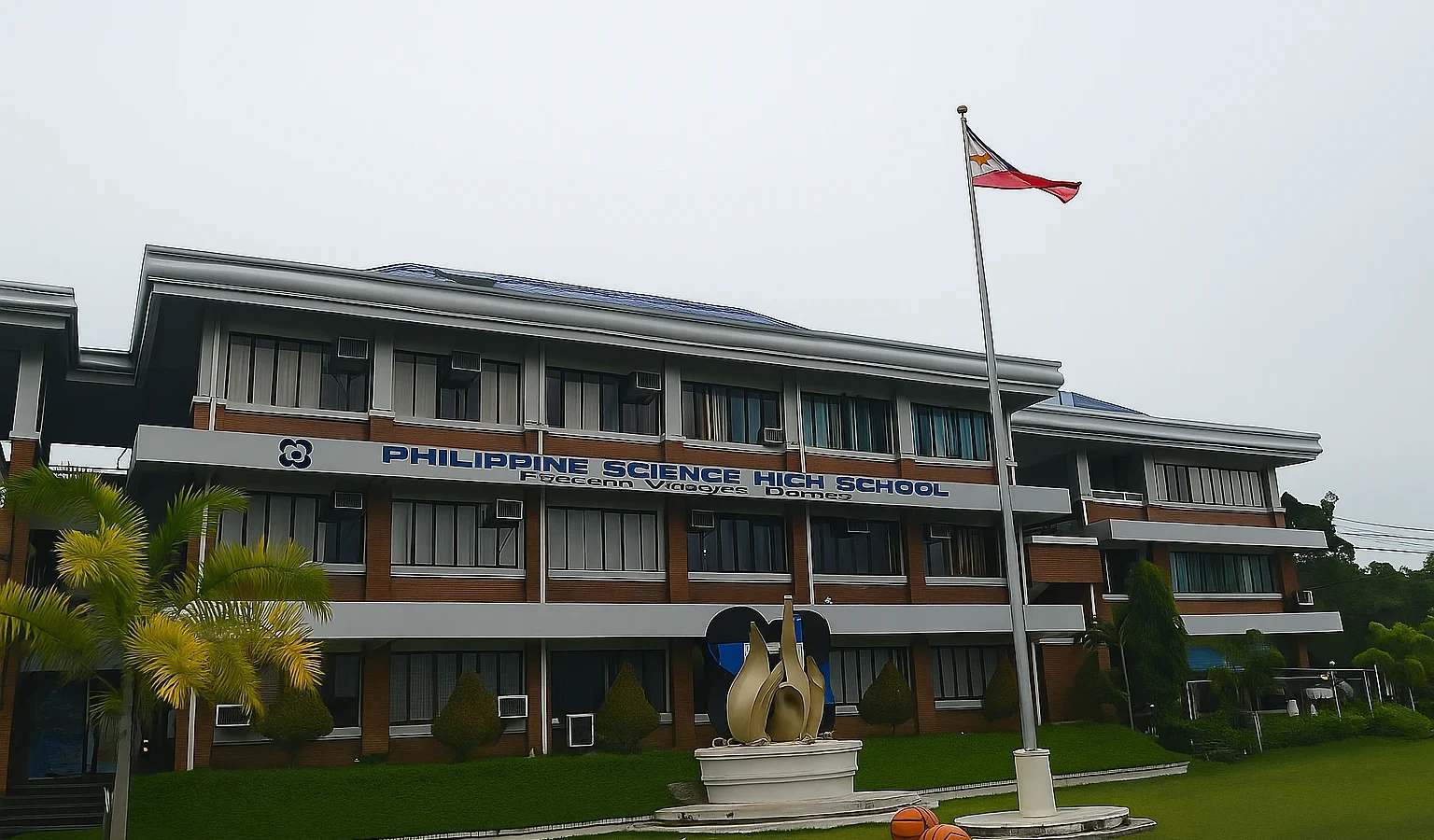 Façade de la Philippine Science High School avec drapeau philippin, bâtiment moderne à deux étages et pelouse verte à l’avant.