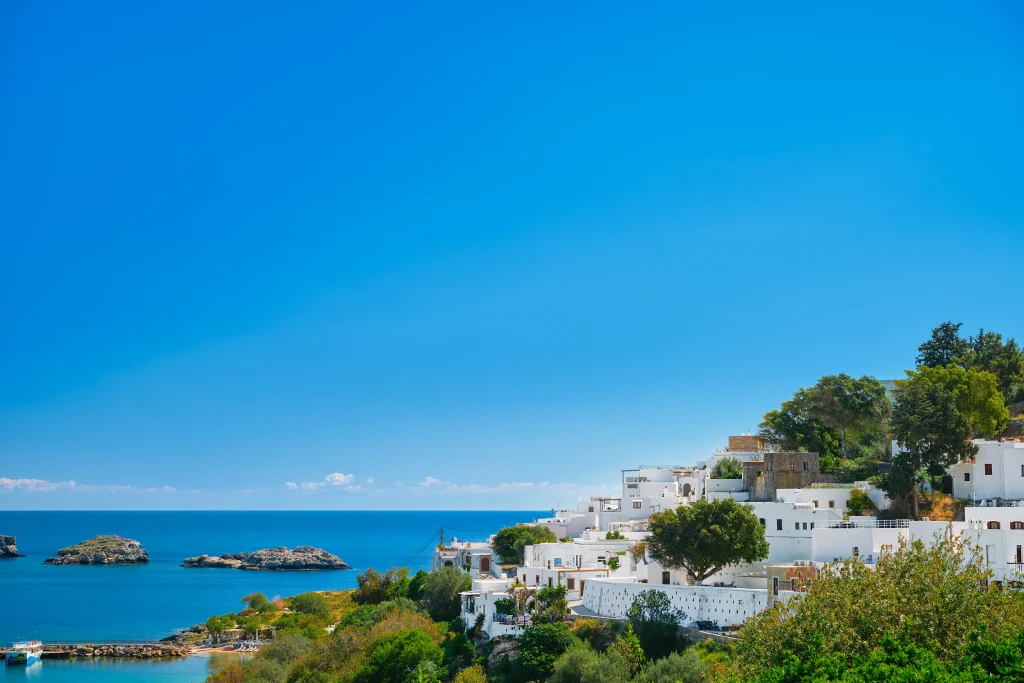 Paysage côtier grec avec maisons blanches face à la mer Égée, cadre de vie idéal pour étudier en Grèce.