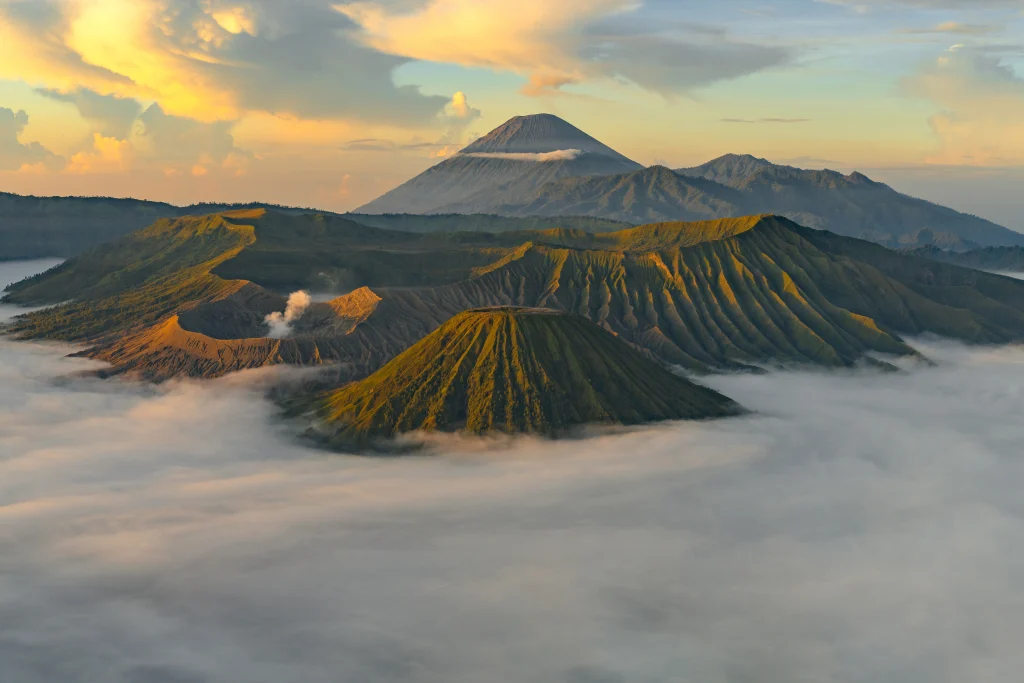 Vue aérienne d’un paysage volcanique en Indonésie, avec les cônes du Bromo et du Semeru au lever du soleil au-dessus d’une mer de nuages.